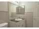 Bright bathroom featuring tiled walls, vanity with countertop, sink, and large mirror at 6601 W Pepperidge Way, Las Vegas, NV 89108