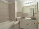 Tiled bathroom featuring a vanity with black countertop, single sink, and tub with shower at 6601 W Pepperidge Way, Las Vegas, NV 89108