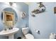 Powder room with round mirror, pedestal sink, blue walls, and unique shelving at 10042 Pipestone St, Las Vegas, NV 89141