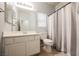 Well-lit bathroom features a single sink vanity and a shower with a gray and white striped curtain at 1598 Cowboy Chaps Pl, Henderson, NV 89002
