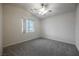 This bedroom has gray carpet, a ceiling fan, and a window overlooking the yard at 1598 Cowboy Chaps Pl, Henderson, NV 89002