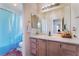 Bathroom featuring a single sink vanity, large mirror, and a shower/tub with a blue shower curtain at 4542 Silver Bit Ct, North Las Vegas, NV 89032