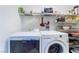 A laundry room featuring a white washer and dryer set with shelves above, great for storage at 4542 Silver Bit Ct, North Las Vegas, NV 89032