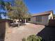 Backyard with rock ground cover, mature trees, covered patio, and perimeter wall at 7572 Coyote Cave Ave, Las Vegas, NV 89113
