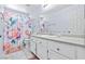Bright bathroom features a white vanity, tile floor, and a decorative floral shower curtain at 2419 Country Orchard St, North Las Vegas, NV 89030