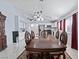 Large dining room with an ornate dark wood table and seating under a modern chandelier with the kitchen visible in the background at 2419 Country Orchard St, North Las Vegas, NV 89030