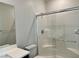 White-tiled shower with a glass door and a white vanity with a large mirror at 4117 Midnight Crest Ave, North Las Vegas, NV 89031