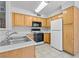 Well-lit kitchen featuring a double sink, wood cabinets and black appliances at 5710 E Tropicana Ave # 1184, Las Vegas, NV 89122