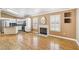Open-concept living area with fireplace, hardwood floors, shutters, and white kitchen cabinetry at 5580 Lonesome Biker Ln, Las Vegas, NV 89113