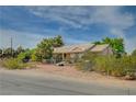 A charming single-story house with a tile roof, set against a backdrop of clear blue skies and lush greenery at 6990 W Richmar Ave, Las Vegas, NV 89178