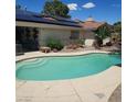 Inviting kidney shaped pool surrounded by a concrete patio, plants and solar panels above at 611 E Fairway Rd, Henderson, NV 89015