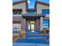 Modern home with a glass front door and stone accents at 10632 Patina Hills Ct, Las Vegas, NV 89135