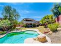 Expansive backyard featuring a beautiful pool, lush lawn, and a charming two-story home at 5301 Fairbranch Ln, Las Vegas, NV 89135