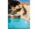Close-up of a luxurious backyard pool showcasing a rock waterfall, spa, and a thrilling water slide at 5301 Fairbranch Ln, Las Vegas, NV 89135