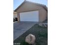 Tan home showcasing the two car garage, concrete driveway, and partial rock landscaping at 3505 Benson Ln, North Las Vegas, NV 89032