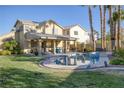 A serene backyard with a covered patio, sparkling pool, and well-manicured lawn with lush landscaping at 1002 Prestige Meadows Pl, Henderson, NV 89052