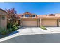 Tan stucco townhouse with a two-car garage and landscaping at 7132 Mission Hills Dr, Las Vegas, NV 89113