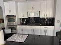 Modern kitchen featuring sleek black countertops, white cabinets, and stainless steel appliances at 2742 Kingclaven Dr, Henderson, NV 89044