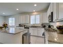 Bright kitchen featuring white cabinets, granite countertops, an island, and stainless steel appliances at 829 N Water St, Henderson, NV 89011