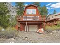 Two-story home with a garage and a balcony, nestled among lush greenery and views of the mountain at 2196 Via Dulcedo St, Mount Charleston, NV 89124