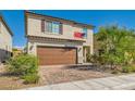 Charming two-story home featuring a brick driveway, two-car garage, and lovely landscaping at 6322 Highledge St, North Las Vegas, NV 89081