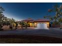 Inviting single-story house with elegant exterior lighting enhancing its curb appeal during the early evening at 1830 E Fuchsia St, Pahrump, NV 89048