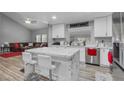 Modern open kitchen and living room with white cabinets, marble countertops, stainless steel appliances and breakfast bar at 7135 Polaris Ave, Las Vegas, NV 89118