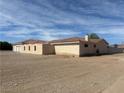 Single-story home featuring an attached two-car garage surrounded by a desert landscape at 1430 Red Rock Dr, Pahrump, NV 89048