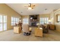 Bright living room featuring a stacked stone fireplace, ceiling fan and many windows at 1214 Country Club Dr, Laughlin, NV 89029