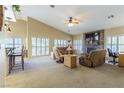 Bright living room featuring a stacked stone fireplace, ceiling fan and many windows at 1214 Country Club Dr, Laughlin, NV 89029