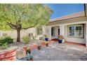 Quaint front courtyard with pavers, potted plants, desert landscaping, and a mature shade tree at 7457 Widewing Dr, North Las Vegas, NV 89084