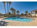 Beautiful community pool area with palm trees, seating, and a nearby building for residents to enjoy at 5701 Pearldrop Ave, Las Vegas, NV 89107