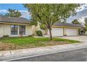 Charming single-story home with a green lawn, mature tree, and attached garages at 5701 Pearldrop Ave, Las Vegas, NV 89107