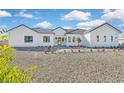 Modern white home with a dark roof, black window trim, and minimal desert landscaping at 6615 Whispering Sands Dr, Las Vegas, NV 89131