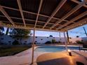 Charming outdoor patio with a pergola strung with lights, adjacent to a pool and lawn, ideal for entertaining at 4369 Greenhill Dr, Las Vegas, NV 89121