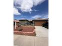 Inviting single-story home with a two-car garage, desert landscaping and a brick border at 5025 Vista Loma Way, North Las Vegas, NV 89031