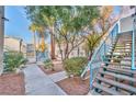 View of a condo building with stairs, mature trees, and landscaped walkway at 4960 Harrison Dr # 214, Las Vegas, NV 89120