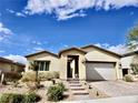 Single-story home with a landscaped front yard, desert landscaping and a two car garage at 44 Strada Caruso, Henderson, NV 89011