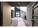 Modern entryway with stone walkway, lush planters, and bright natural light streaming through glass doors at 612 Dragon Mountain Ct, Henderson, NV 89012