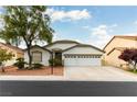 Three-car garage home with desert landscaping and a large tree at 8405 Bonnie Blue St, Las Vegas, NV 89143