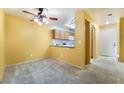 View of a large living room and eat in kitchen with carpet flooring and light yellow walls at 10332 Perfect Parsley St, Las Vegas, NV 89183