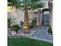 Inviting front entrance with a tiled walkway, lush landscaping, and a decorative palm tree at 11261 Playa Caribe Ave, Las Vegas, NV 89138