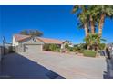 Long driveway leading to a two-car garage and a meticulously landscaped front yard with vibrant flowers and manicured bushes at 485 Sari Dr, Las Vegas, NV 89110