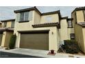 Tan two-story house with a brown garage door and landscaping at 11416 Belmont Lake Dr # 102, Las Vegas, NV 89135