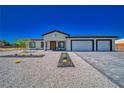 Modern single-story house with a three-car garage and desert landscaping at 1691 Blackhorn St, Pahrump, NV 89048