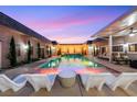 Inviting backyard pool area with lounge chairs, outdoor lighting, and colorful sunset sky at 647 Foxhall Rd, Henderson, NV 89002