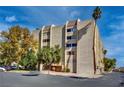 Exterior view of a residential building with a parking lot and mature trees on a sunny day at 730 S Royal Crest Cir # 421, Las Vegas, NV 89169