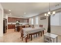 Open-concept kitchen and dining area with a chandelier, featuring stainless steel appliances and tile flooring at 7579 Harwich Bay Ave, Las Vegas, NV 89179