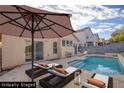 Backyard with a sparkling blue pool, patio furniture, an umbrella, and exterior home views at 7936 Pinnochio Ave, Las Vegas, NV 89131