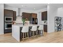 Kitchen island with quartz countertops, seating for three, stainless steel appliances, and dark wood cabinetry at 9002 Shifting Skye St, Las Vegas, NV 89166